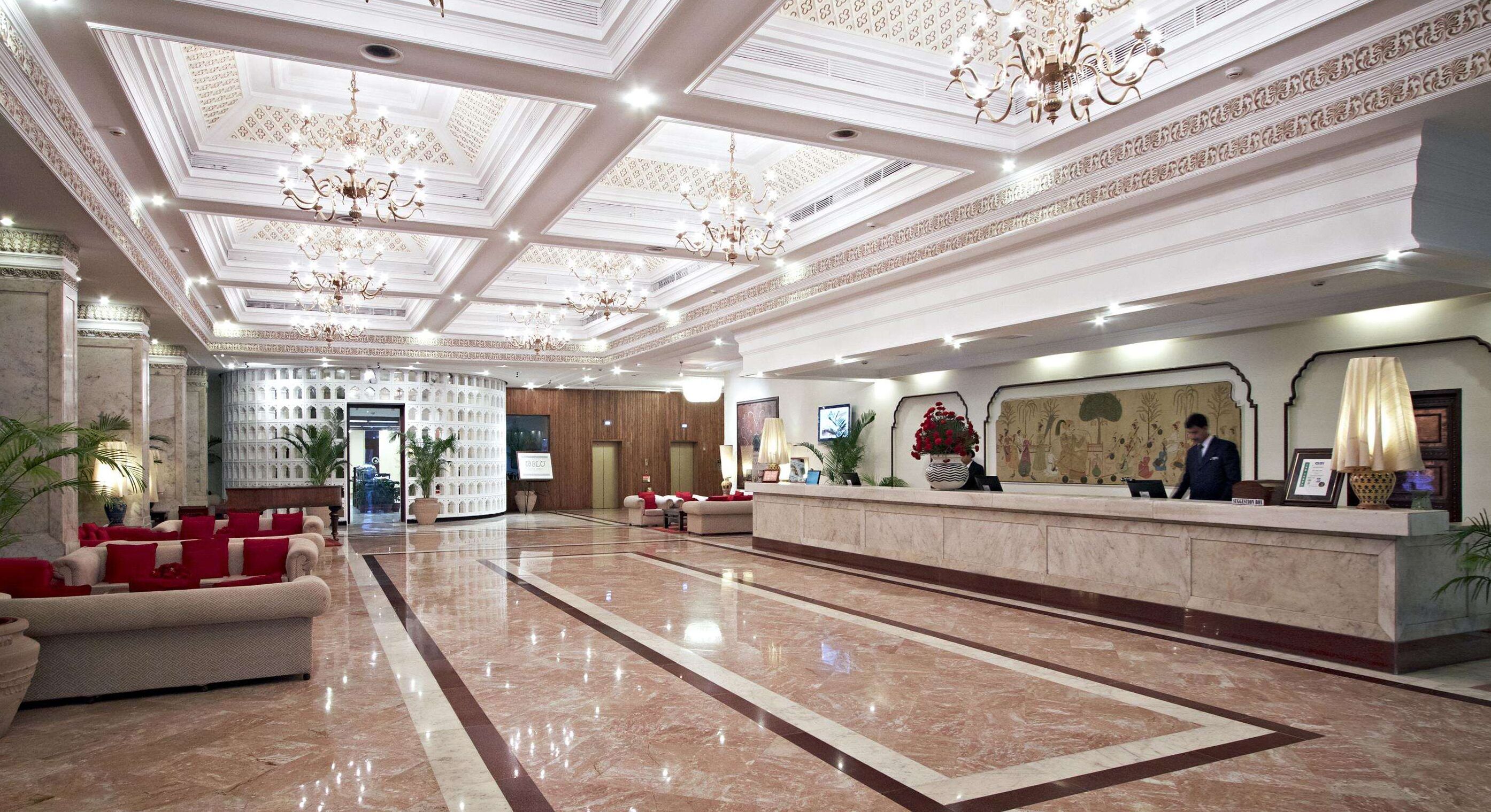 Un hall espacioso con piso de mármol, una recepción y un candelabro.