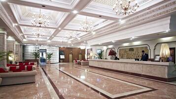 Un hall espacioso con piso de mármol, una recepción y un candelabro.