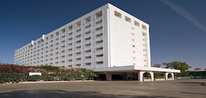 A large, white, multi-story hotel with a symmetrical facade and a central entrance.