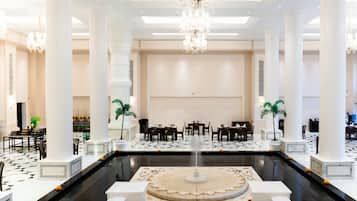 Un hall amplio con una fuente central, techos altos y columnas de estilo clásico.