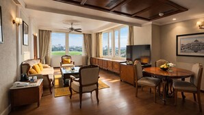 A hotel room with a dining area, a sofa, a television, and a large window with a view. - Clarks Avadh, Lucknow (Lucknow)