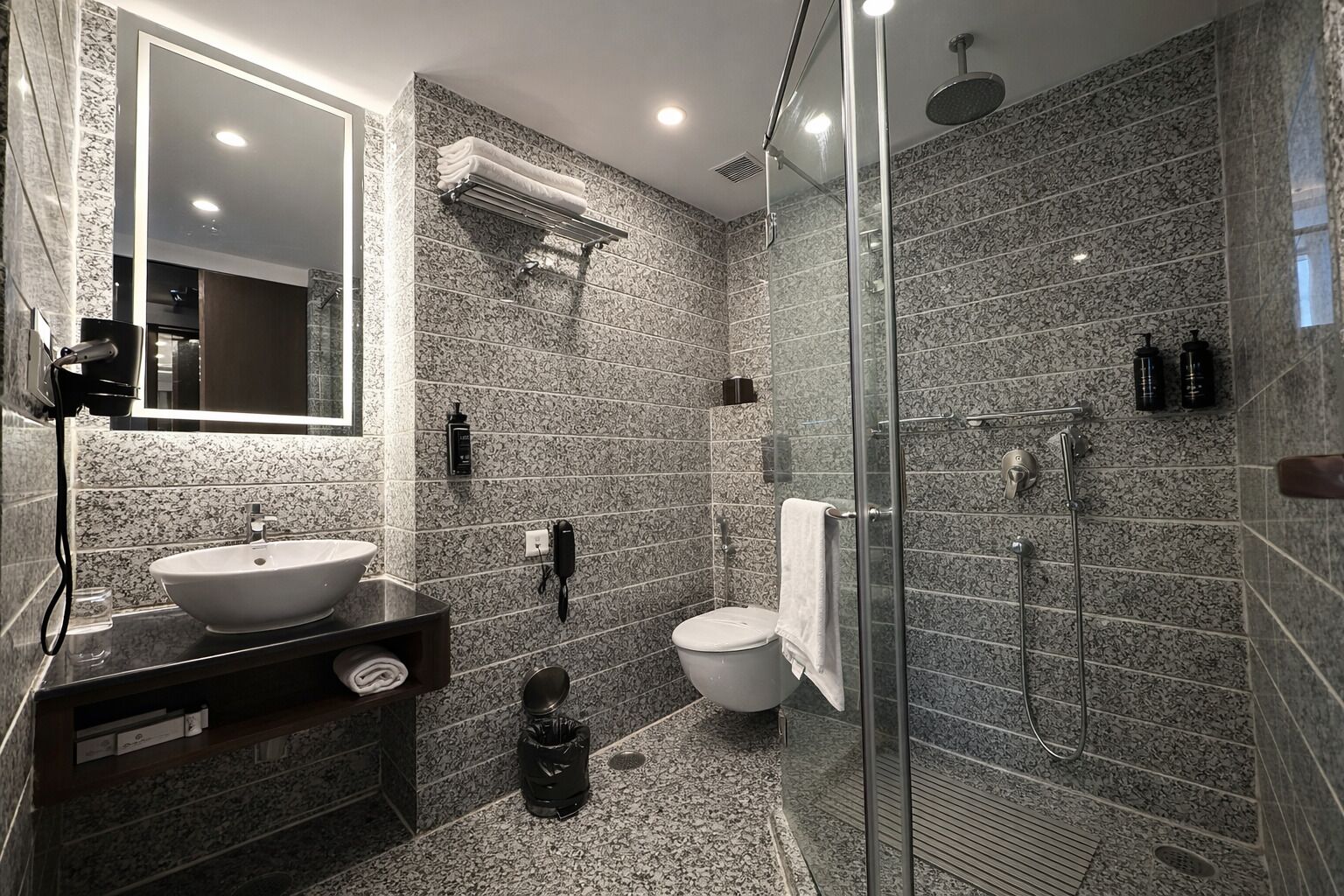 A modern bathroom with a large mirror, a sink, a toilet, and a shower area.