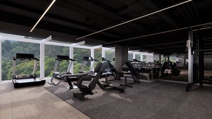 A modern gym with treadmills, weight machines, and a large window overlooking a forested area. - Padma Hotel Bandung (Bandung)