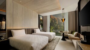 A modern hotel room with two beds, a sofa, a TV, and a large window with a view. - Padma Hotel Bandung (Bandung)
