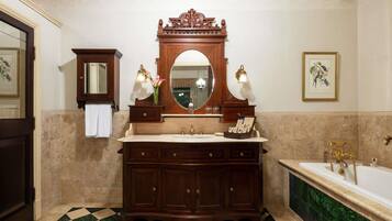 Casa de banho com chão xadrez, espelho grande, toucador com lavatório e banheira.