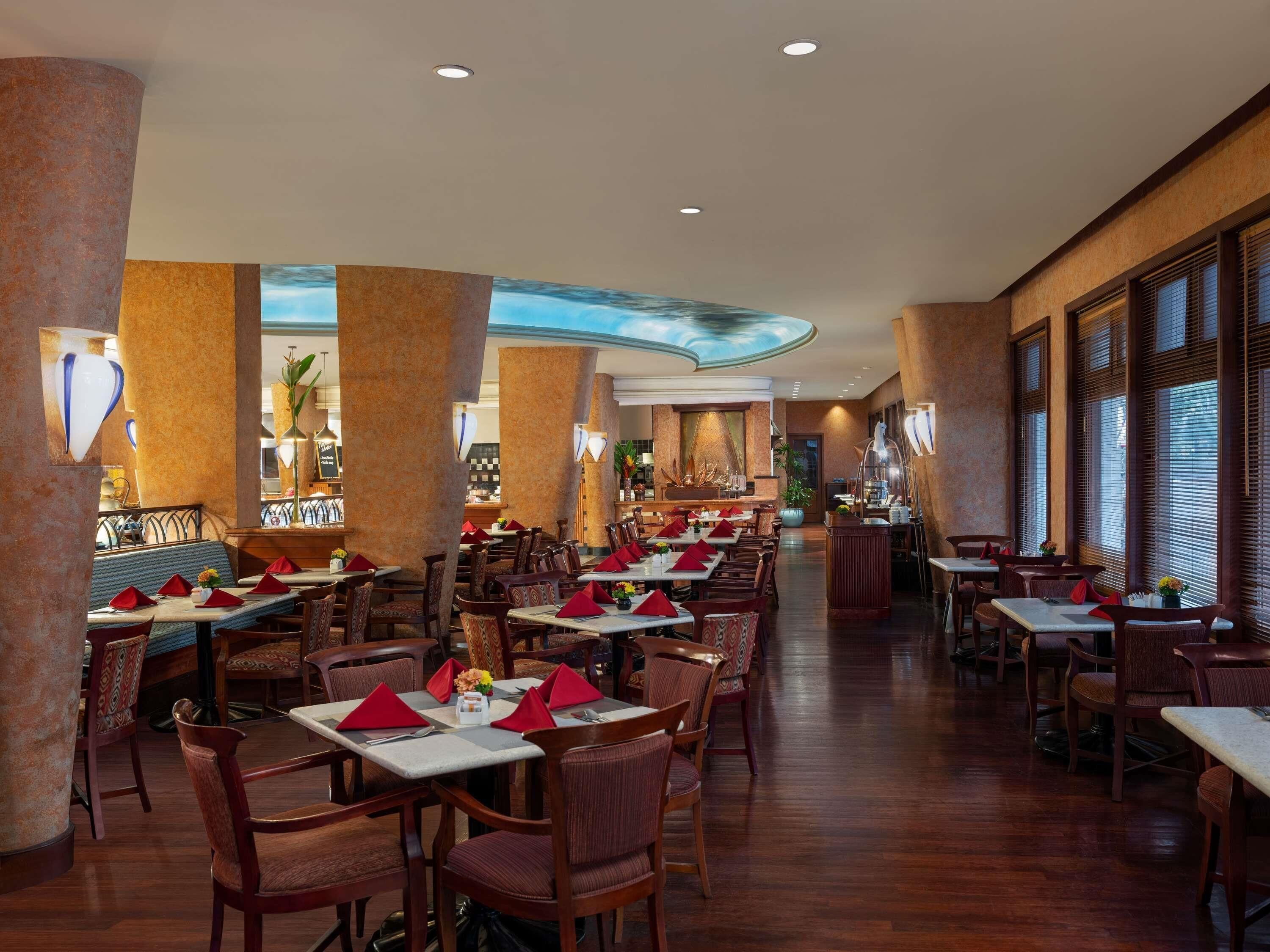 A spacious restaurant with high ceilings, wooden flooring, and a variety of seating arrangements including tables and chairs.
