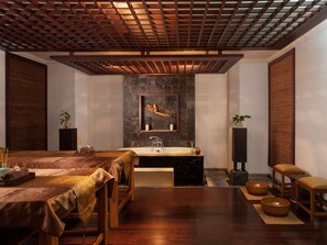 Un cuarto de spa con techo de madera, pared de piedra, una obra de arte enmarco y muebles de madera, además de una bañera.