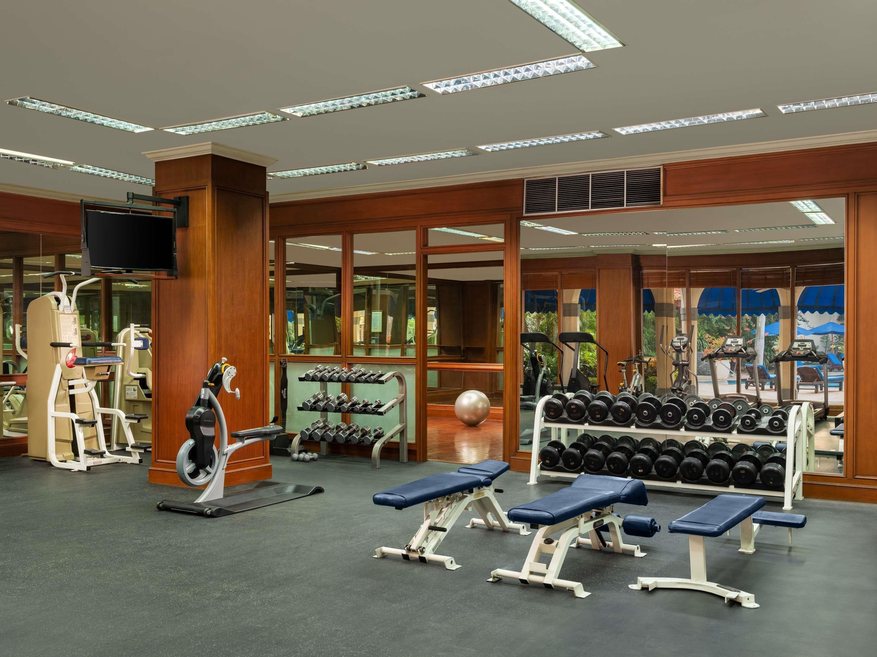 Een sportschool met trainingsapparatuur, gewichtrekken en banken.