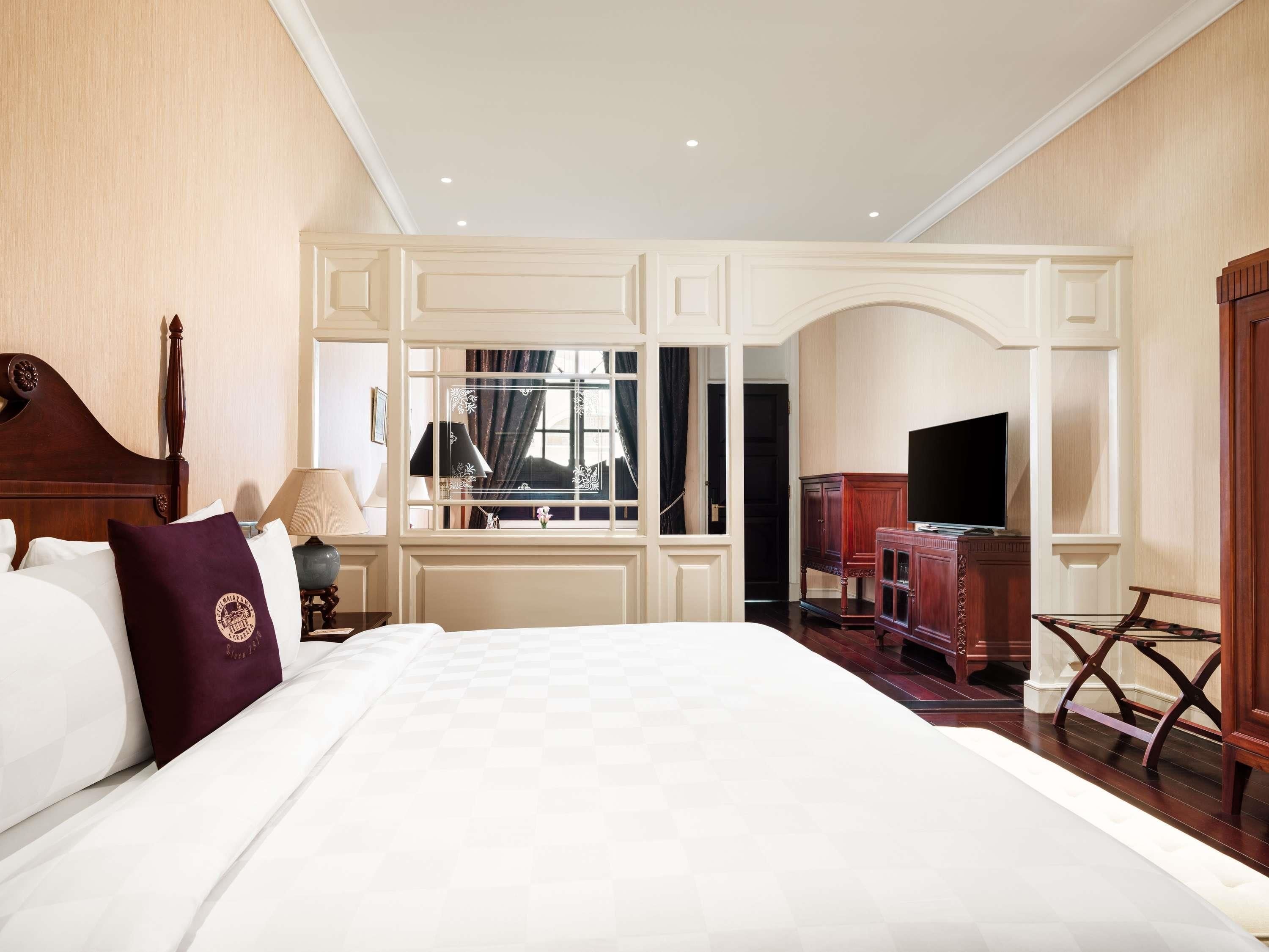 A hotel room with a large bed, a television, a desk, and a mirror.