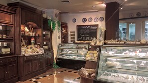 Eine Bäckerei mit Holzschränken, einer Verkaufstheke voller Gebäck und einer Kreidetafel mit Speisekarte.