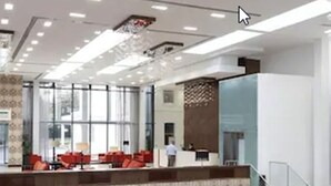 Un hall d’hôtel spacieux, doté d’un plafond haut, de plusieurs espaces aménagés pour s’asseoir et d’un escalier menant à un étage supérieur.