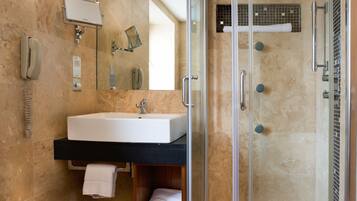 A modern bathroom with a glass-enclosed shower, a sink with a towel, and a mirror.