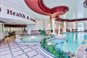 A large indoor swimming pool with a checkered floor, surrounded by a decorative pool edge and plants. - Rochestown Park Hotel (Douglas)