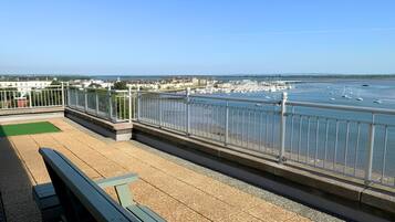 A waterfront promenade with a bench and railing, overlooking a marina with boats.