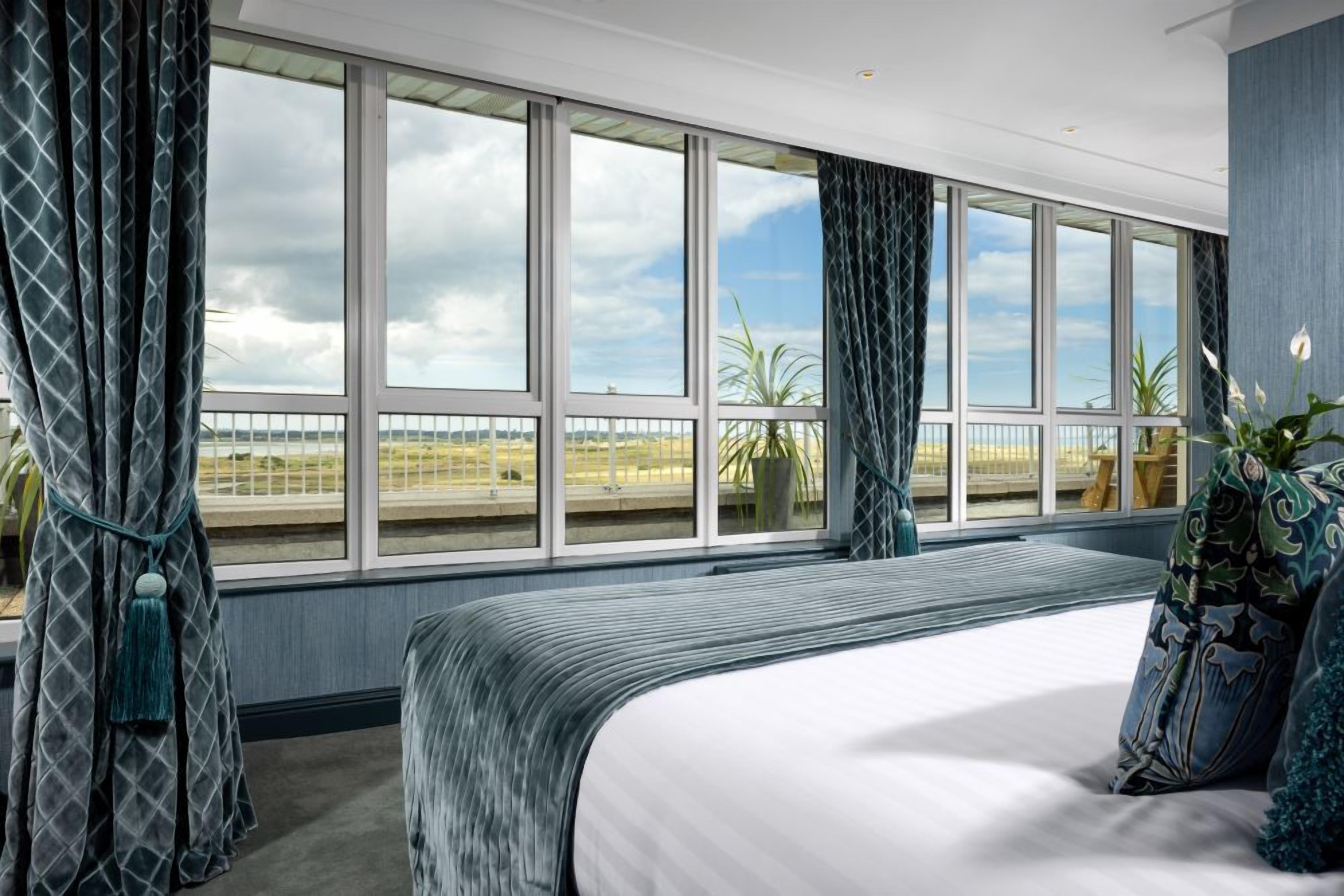 Une chambre avec un grand lit, une vue sur la plage et un balcon doté d’une balustrade.