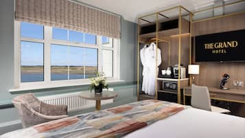 A hotel room with a large bed, a seating area, a TV, a wardrobe, and a view of the outdoors.