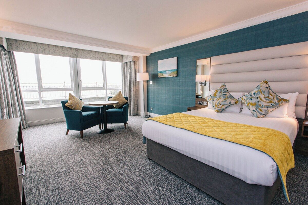 Habitación de hotel con cama, escritorio, silla y vistas a la ciudad.