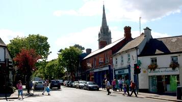 A street scene with pedestrians, cars, and buildings, including a pharmacy and a church spire.