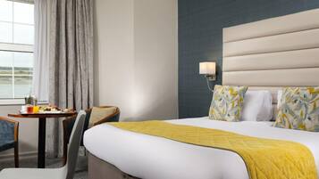 Habitación de hotel con cama, escritorio con desayuno, una silla y vistas al exterior.