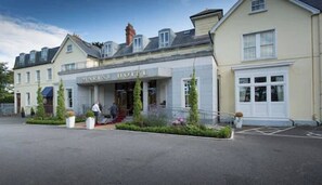Kaksikerroksinen rakennus, jonka yläpuolella on kyltti, jossa lukee ”MARINE HOTEL”. Kaksi ihmistä kävelee sisäänkäynnin edessä.