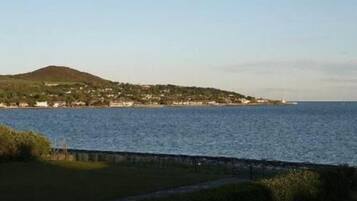 A coastal view with a hill and a small settlement by the sea.