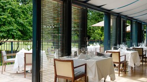 A restaurant with outdoor seating, tables set with white tablecloths, and chairs. - Herbert Park Hotel (Dublin)