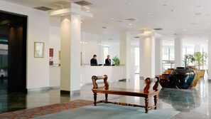 A modern hotel lobby with a reception desk, a wooden bench, and a large vase. - Herbert Park Hotel (Dublin)
