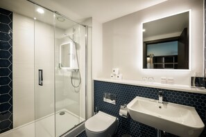 Enjoy a refreshing shower in the bathroom, featuring a glass-enclosed shower, pedestal sink, and toilet.