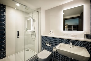 Enjoy a refreshing shower in the bathroom, featuring a glass-enclosed shower, pedestal sink, and toilet.