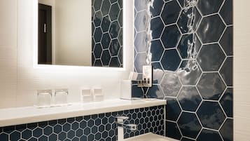 A bathroom with a white sink, a mirror, and a wall with hexagonal tiles.