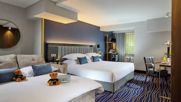 A hotel room with two beds, a sofa, a desk, a chair, and a mirror.