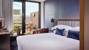 A hotel room with a large bed, a desk with a lamp, a chair, and a view of the outdoors. - The Grafton Hotel (Dublin)