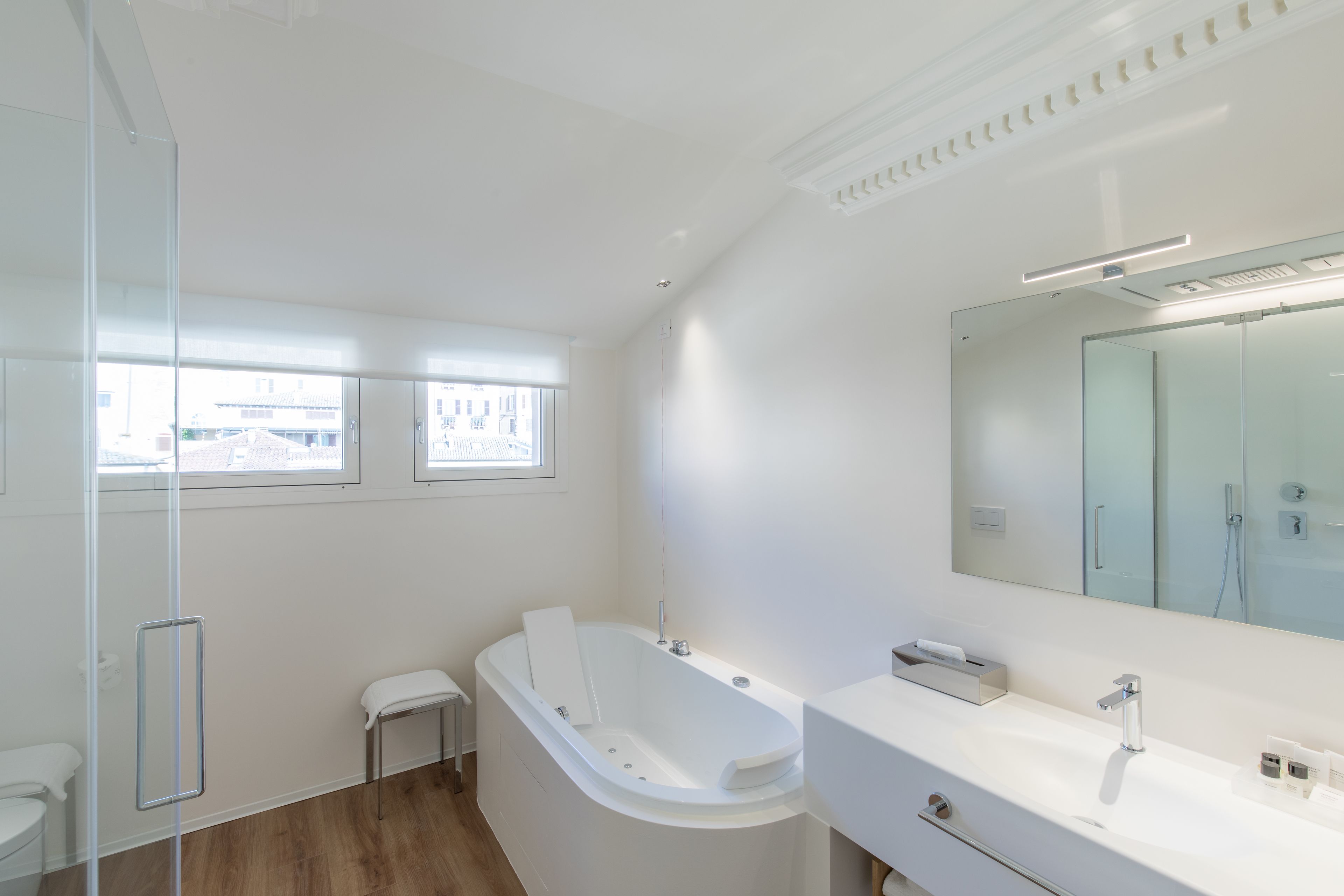 Un baño moderno con una bañera independiente, un espejo grande y un tocador blanco.