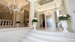 Een statige trap met witte treden en versierde witte vazen met bloemen op de verdieping.
