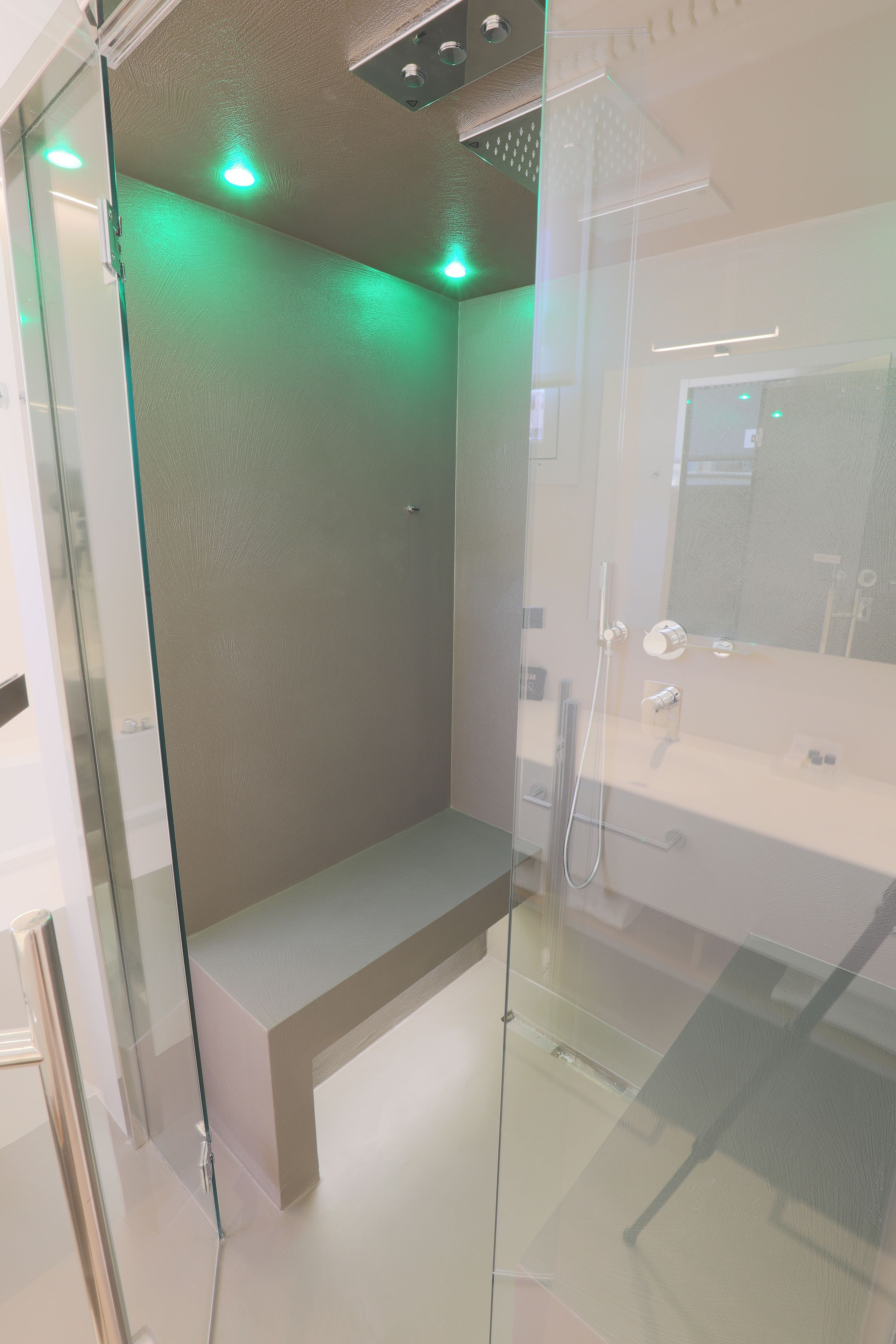 Een moderne badkamer met een douchecabine van glas, een bankje en een vrijstaand bad.