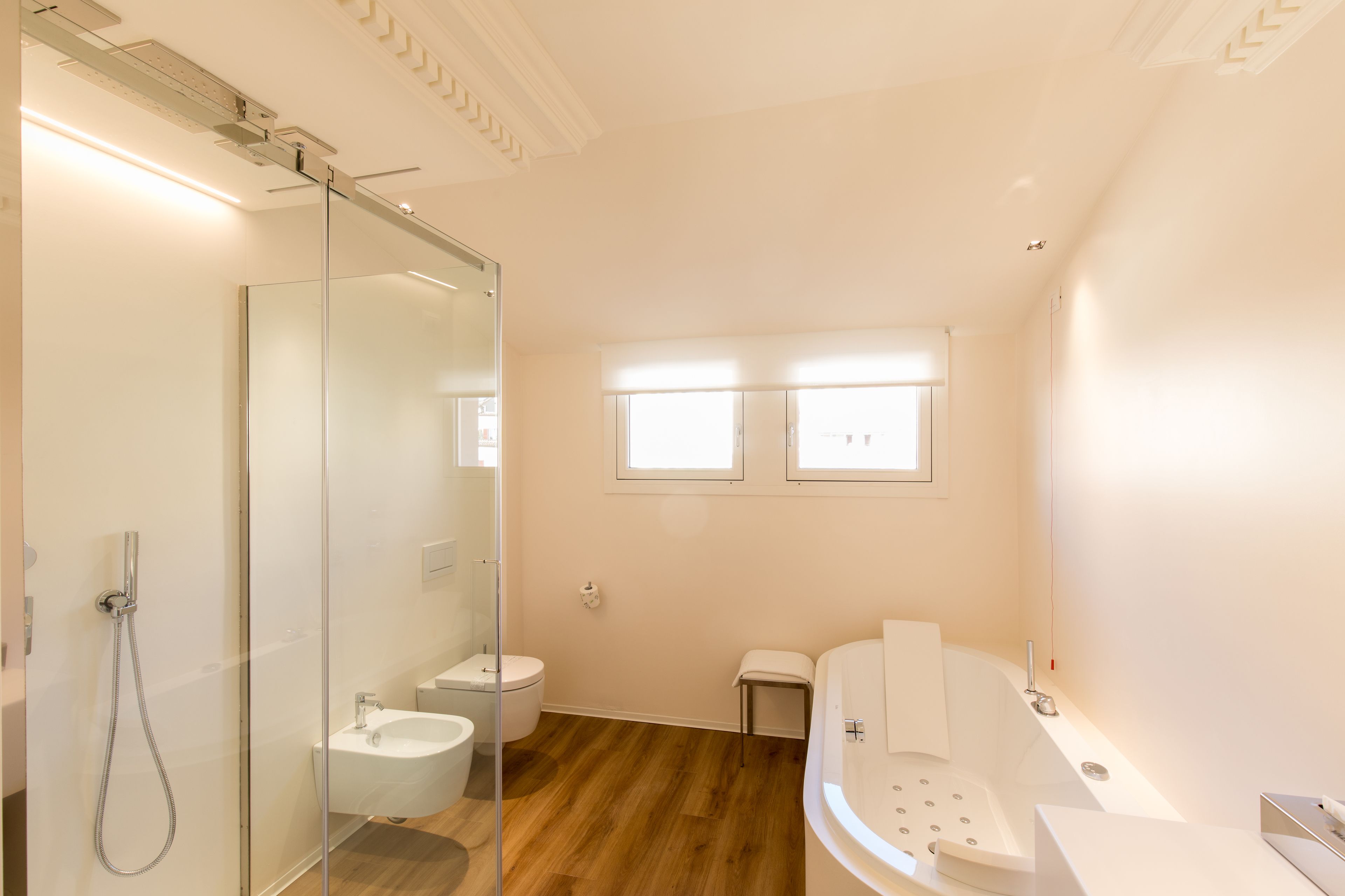 A modern bathroom with a glass shower enclosure, a freestanding bathtub, and a toilet.