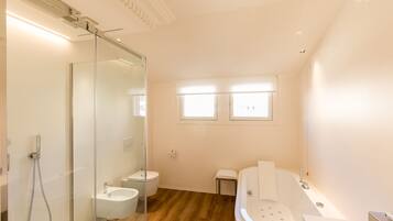 A modern bathroom with a glass shower enclosure, a freestanding bathtub, and a toilet.