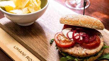 A burger with a sesame seed bun, tomato slices, and a side of chips.