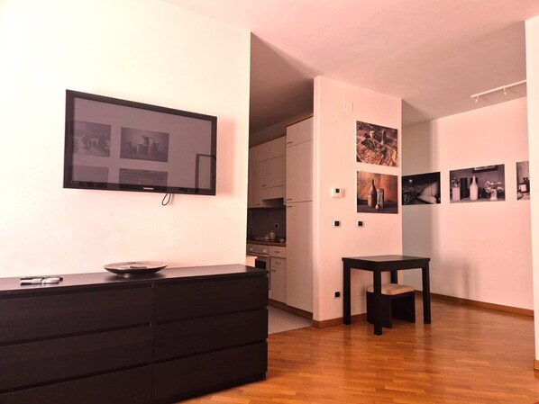 Una sala de estar moderna con un televisor de pantalla plana, un mueble de entretenimiento negro y una mesita.