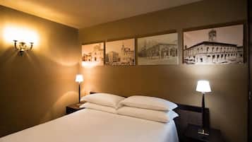 Een hotelkamer met een bed, twee bedlampen en vier ingelijste foto’s aan de muur.