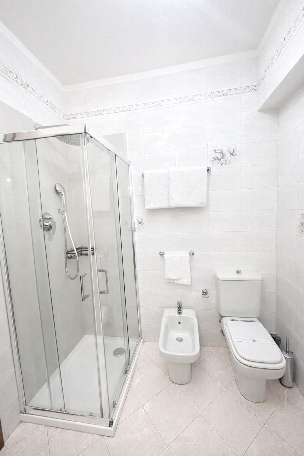 Een moderne badkamer met een douchecabine van glas, een toiletbrons en een wc.