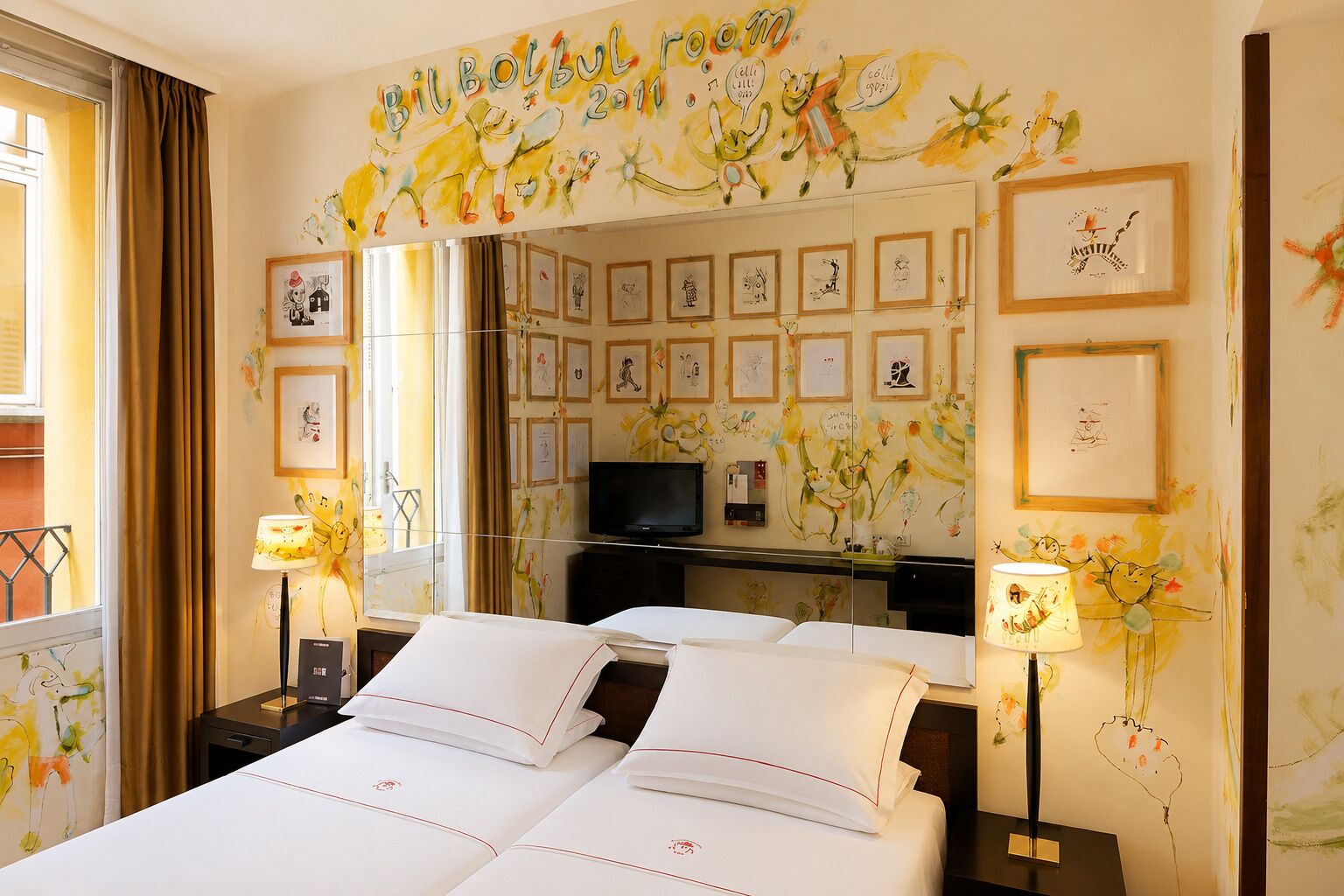 A hotel room with a large bed, a TV, and artwork on the walls.