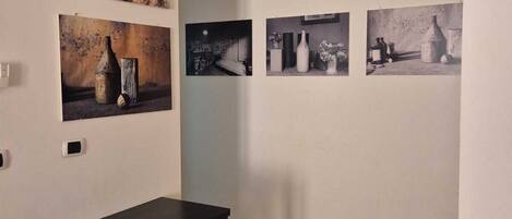 A gallery with a wooden floor, a black table with a bench, and four black-and-white photographs on the wall.