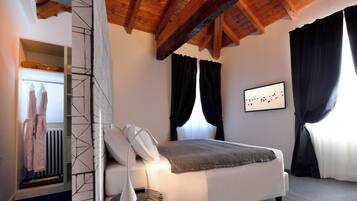 Un dormitorio con cama, lámpara de noche, radiador y un cuadro en la pared.
