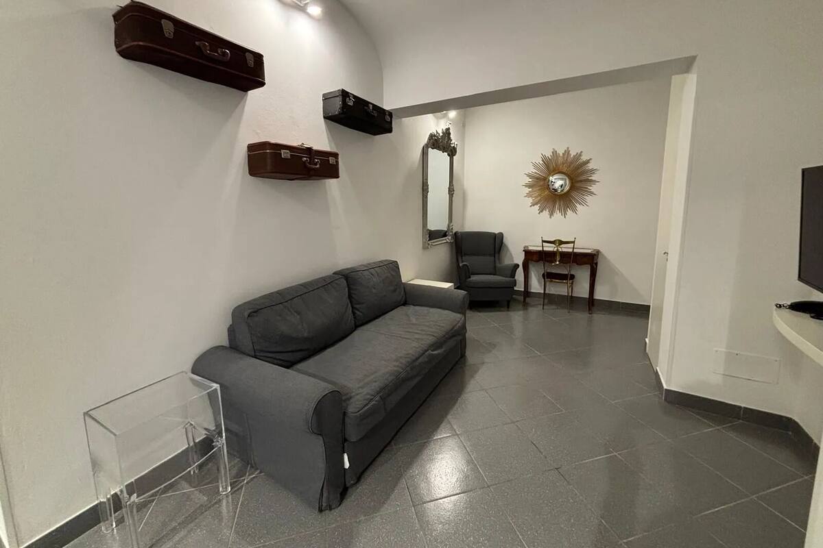 Un salon moderne avec un canapé gris, une petite table, un fauteuil et un téléviseur posé sur un meuble.