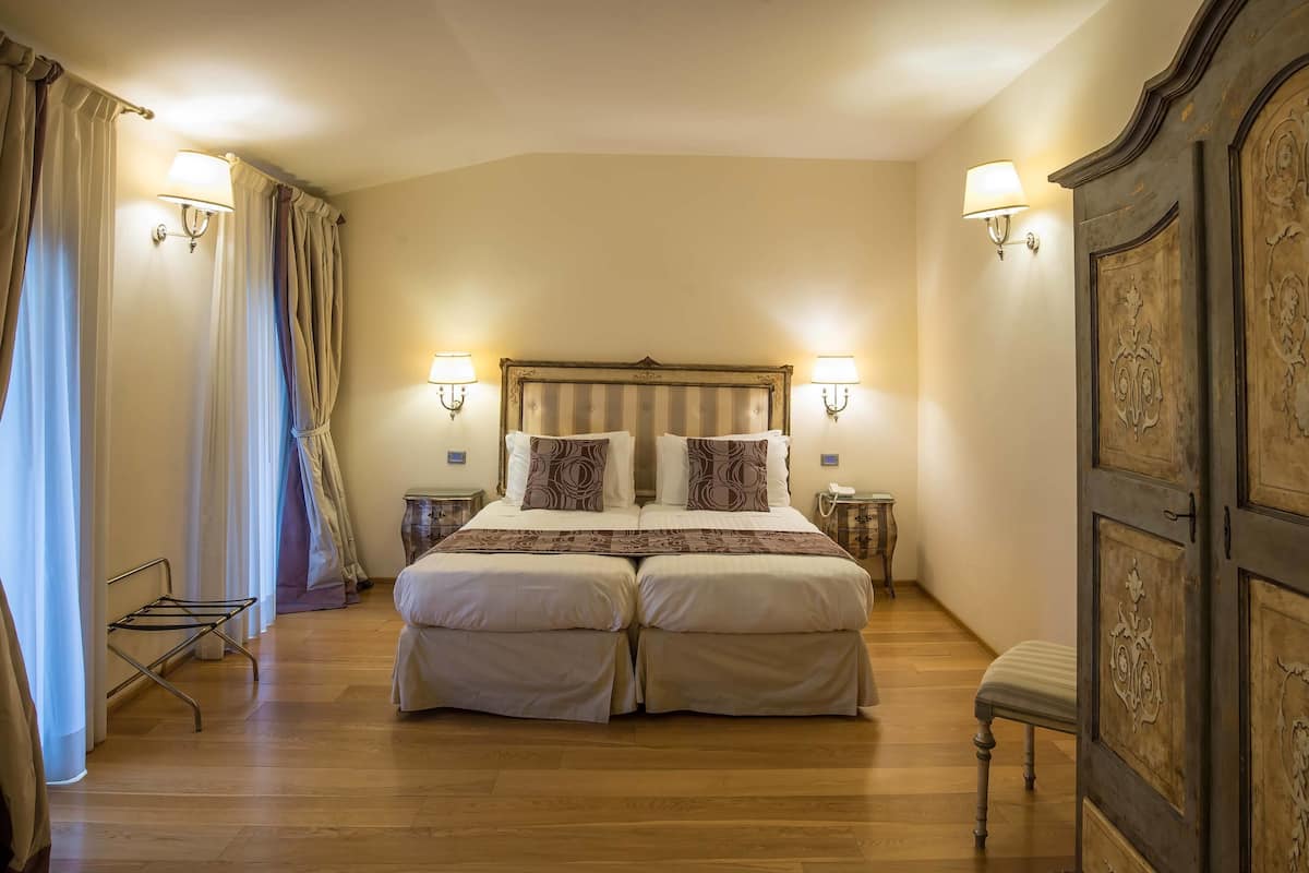 A double bed with two nightstands, a bench, and a wardrobe.