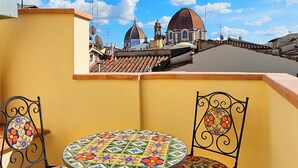 A balcony with a round table and two chairs, overlooking a cityscape with domed buildings and a clear sky. - Hotel Atlantic Palace (Florence)