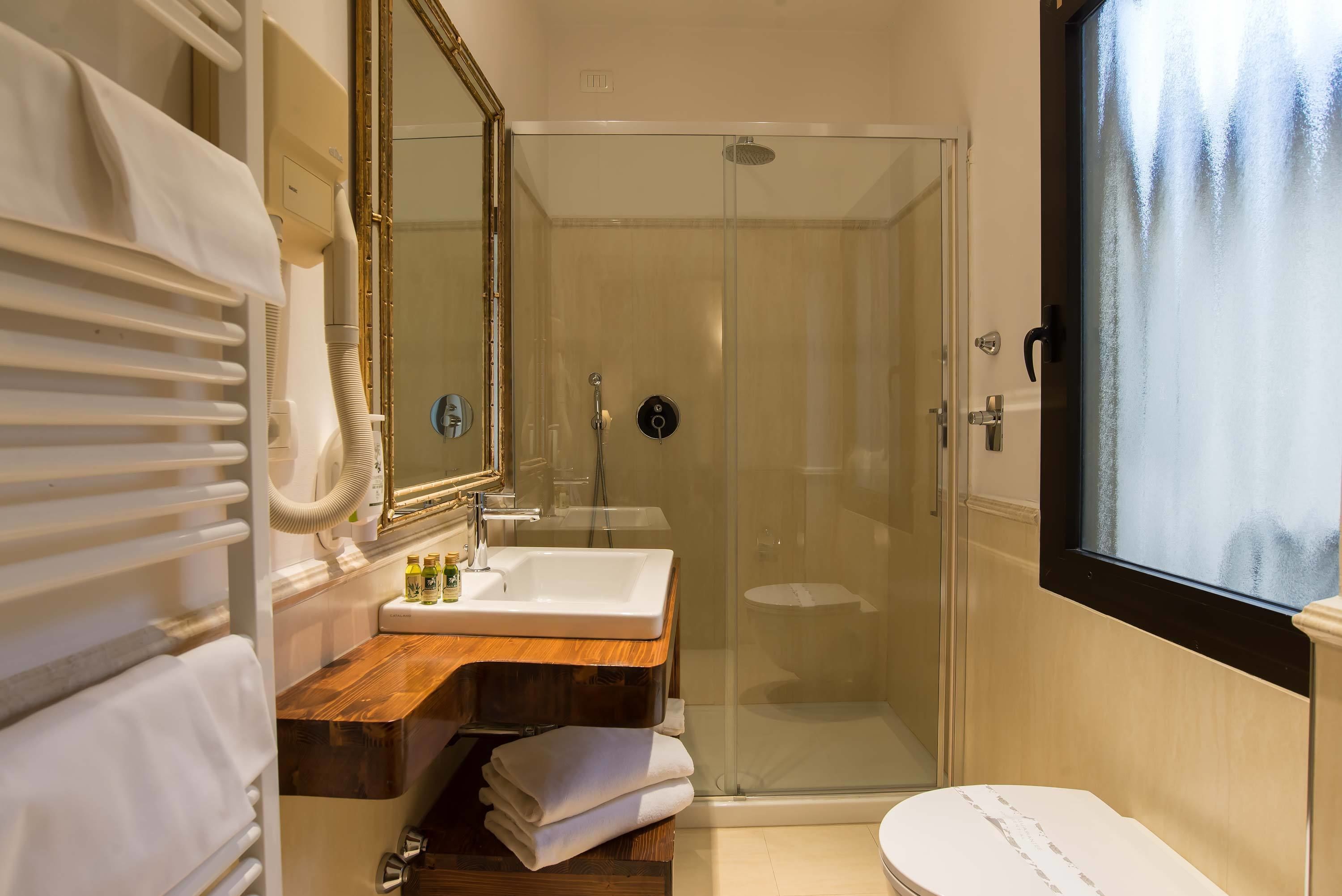 A bathroom with a glass-enclosed shower, a wooden vanity, a white sink, and a large mirror.