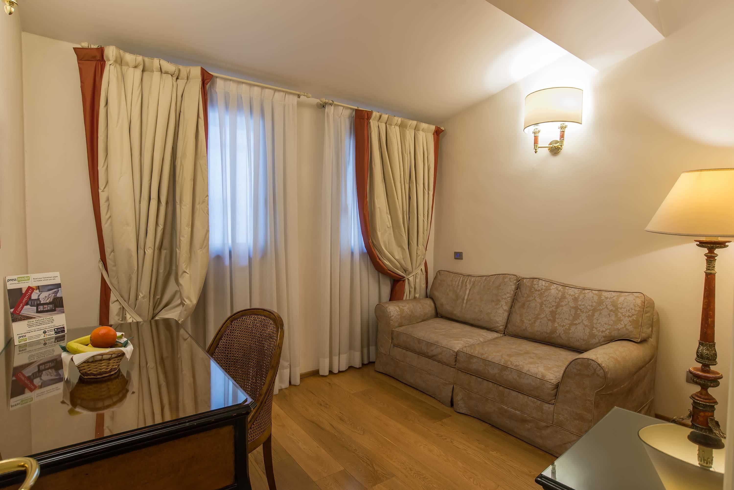 Quarto com sofá, poltrona, luminária e mesa com cesta de frutas.