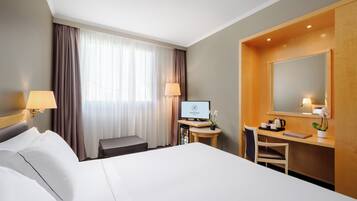 Une chambre d’hôtel équipée d’un lit, d’un bureau, d’une chaise, d’une lampe et d’un téléviseur.